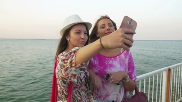 Дівчата беруть селфі на понтон з морем як фон — стокове відео