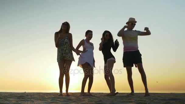 Друзья танцуют на пляже на рассвете — стоковое видео