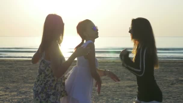 Drie mooie jonge vrouwen die dansen op het strand bij zonsopgang — Stockvideo