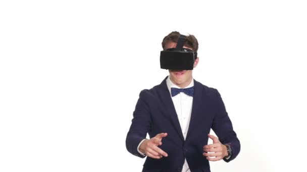Jovem homem elegante em um estúdio com fundo branco jogando um jogo de realidade virtual — Vídeo de Stock