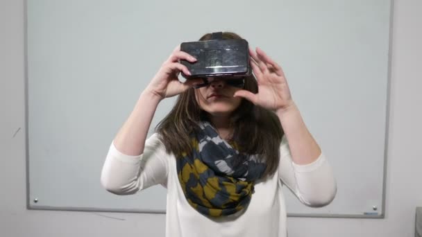 Женщина испытывает очки виртуальной реальности в классе с доской позади — стоковое видео