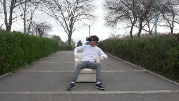 Jonge man dragen Vr headset zitten in een leunstoel binnenkomt virtuele werkelijkheid wereld en wordt verrast — Stockvideo