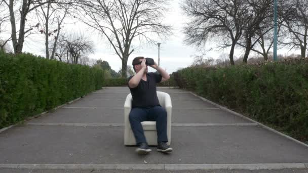 Guy met behulp van Vr bril specifieke gebaren en rondkijken in het park — Stockvideo