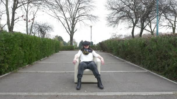 Vrouw gebruikt Vr apparatuur terwijl u ontspant in een fauteuil in een park — Stockvideo