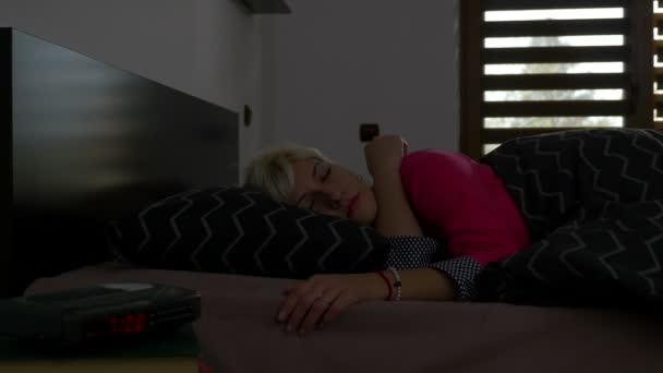 Blonde jonge vrouw alarm uitschakelen in de ochtend en terug te gaan om te slapen — Stockvideo