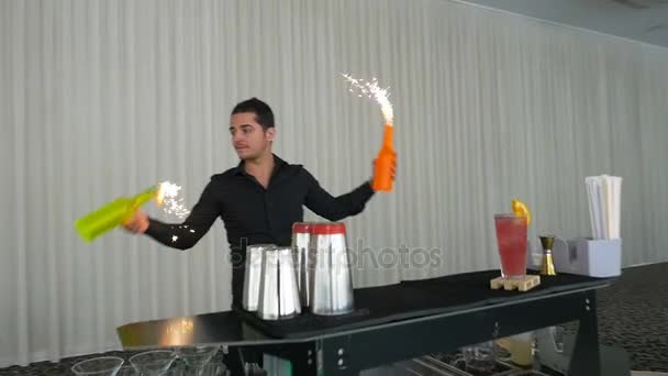 Barman jonglering och att göra flair bartending flyttar på en bar med flaskor och fyrverkerier — Stockvideo