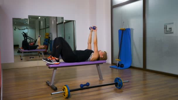 Mujer entrenando en el gimnasio en el banco con pesas — Vídeo de stock