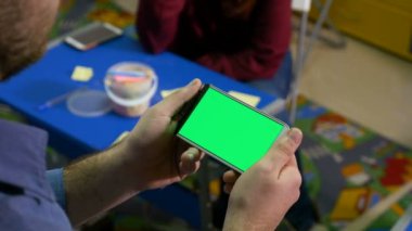 Bir grup insan bir atölye ve adam holding smartphone yeşil ekran ile beyin fırtınası