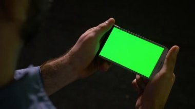 Yeşil ekranlı akıllı telefon üzerinde medya içeriği izleyen adamım