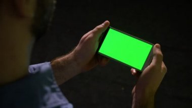 E-posta ve diğer uygulamaları kontrol etmek için yeşil ekran akıllı telefon kullanarak genç iş adamı