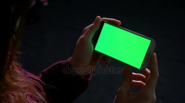 Bir akıllı telefon ile yeşil perde tutarak ve swiping kadının elleri