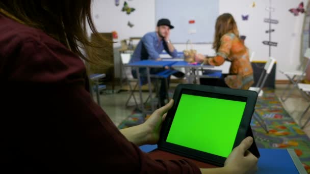 Підлітки в класі спілкуються з зеленим екраном планшетного ПК — стокове відео
