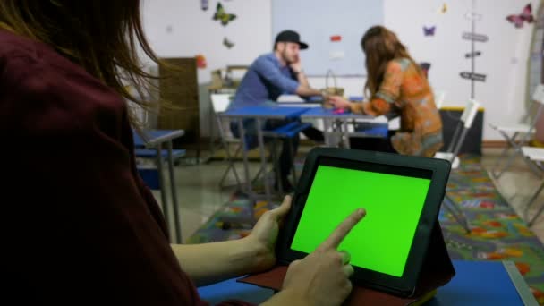 Hombres y mujeres jóvenes en una sala de taller con tableta de pantalla verde PC — Vídeo de stock
