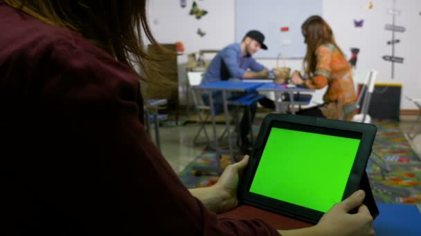 Tonåring flicka att svepa TabletPC sitter vid skrivbord i klassrummet och en pojke en flicka sitter på ett annat skrivbord — Stockvideo