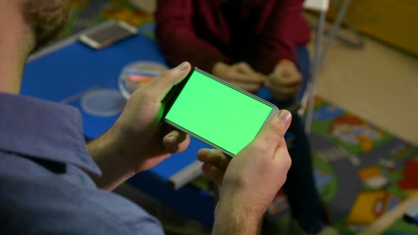 Мальчик смотрит смартфон с зеленым экраном и учит девушку — стоковое видео