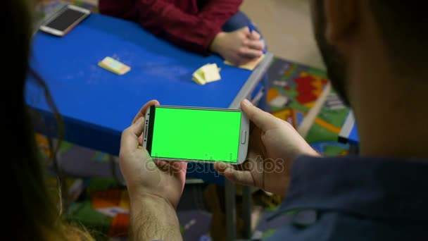 Три студента участвуют в семинаре в классе и смотрят телефон с зеленым экраном — стоковое видео