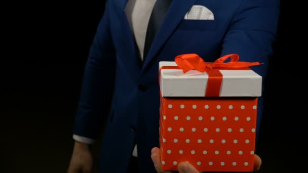 Close up van een hand van een man bedrijf en tonen geschenkdoos met rood lint — Stockvideo