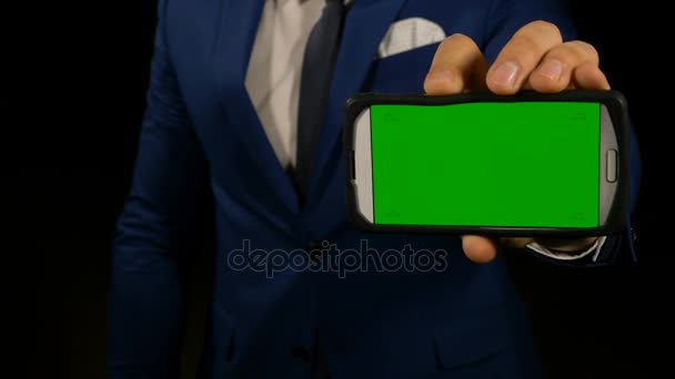 Рука человека, держащего смартфон с зеленым экраном и указывающего пальцем на дисплей — стоковое видео