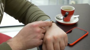 Kahve dükkanında otururken smartwatch e-posta uygulaması kullanan genç adam