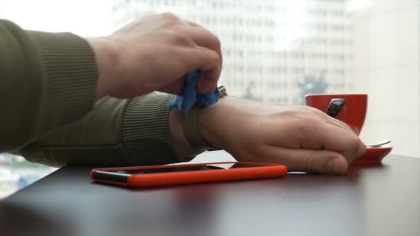 Człowiek do czyszczenia ekranów smartwatch i inteligentny telefon w kawiarni — Wideo stockowe