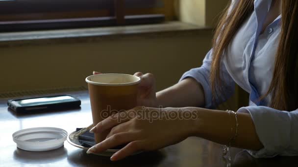 Kezében egy nő forró ital tartályban, elhelyezés egy befedni-rajta és egy kávézóban iszik a beszéd — Stock videók