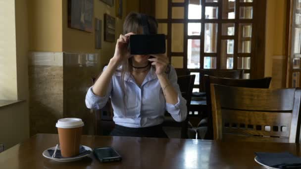 Jovem atraente coloca em VR óculos de realidade virtual no café — Vídeo de Stock