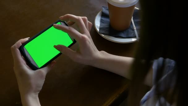 Vingers van een vrouw maken zoom in en uit gebaren op smart phone met groen scherm in een café — Stockvideo