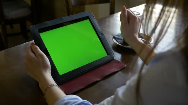 Mulher sentada em uma mesa usando tela verde tablet pc e fazendo zoom dentro e fora gestos em um café — Vídeo de Stock