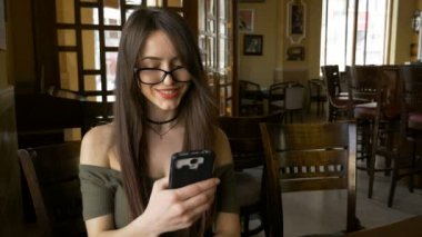 Restoran bir masada oturan ve medya içeriği onun akıllı telefon üzerinde izlemek iş kadını