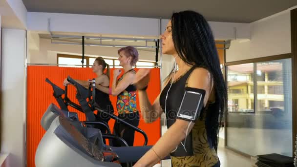 Mujer fitness con brazalete para smartphone escuchando música y haciendo actividad deportiva en la cinta de correr — Vídeos de Stock