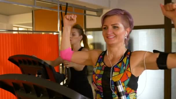 Wanita paruh baya yang bahagia mengenakan pelacak kebugaran menikmati musik dan berolahraga di klub olahraga — Stok Video