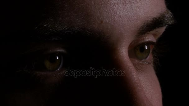 Acercamiento macro de los ojos del hombre joven mirando y buscando en la oscuridad — Vídeos de Stock