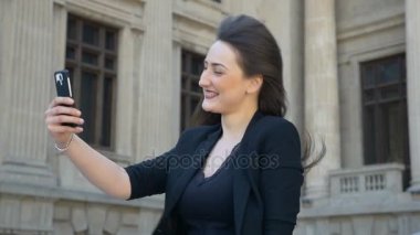 Başını eğme ve yavaş hareket ederken o selfie için smartphone kullanarak saçlarını saygısız güzel kız