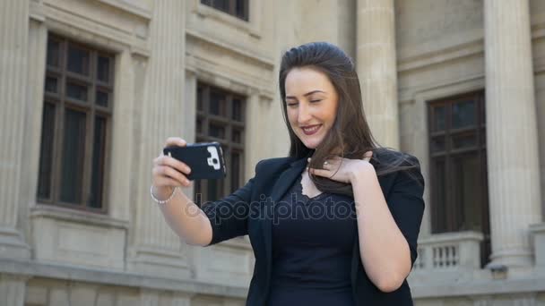 Zeitlupe einer attraktiven Frau, die ein Video-Selfie macht, während sie ihr schönes braunes Haar wedelt — Stockvideo