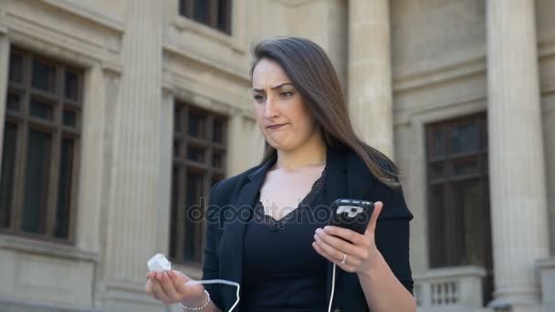 Chica molesta en la ciudad con teléfono inteligente descargado preguntándose cómo cargar la batería — Vídeo de stock