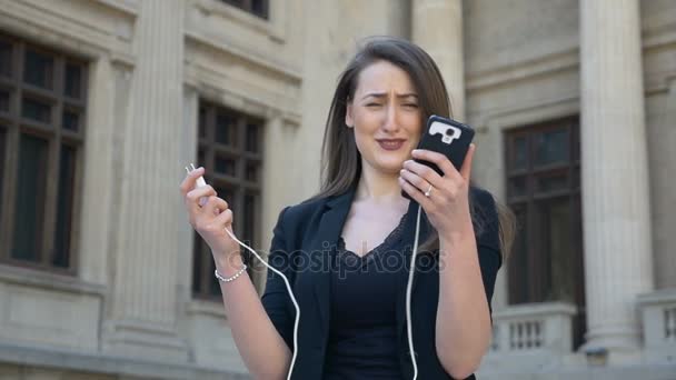 Νεαρή γυναίκα θυμωμένος και ανήσυχος, κλαίει, ενώ το τηλέφωνο απενεργοποιείται ενώ λόγω αποφορτισμένη μπαταρία χαμηλή στην πόλη — Αρχείο Βίντεο