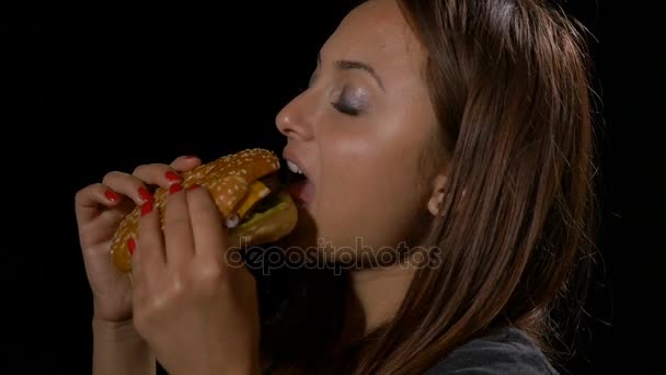 Vista del perfil de la encantadora mujer comiendo una hamburguesa en cámara lenta — Vídeos de Stock