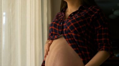 Gülümseyen ve yavaş yavaş onun doğmamış bebeğin göbek düşünmeye dokunmadan mutlu hamile kadın