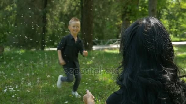 Menino correndo para abraçar a mãe sendo feliz e sorrindo na natureza — Vídeo de Stock