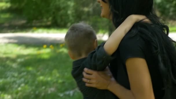 Close-up van jonge moeder knuffelen en ronddraaien van haar zoon in het park — Stockvideo