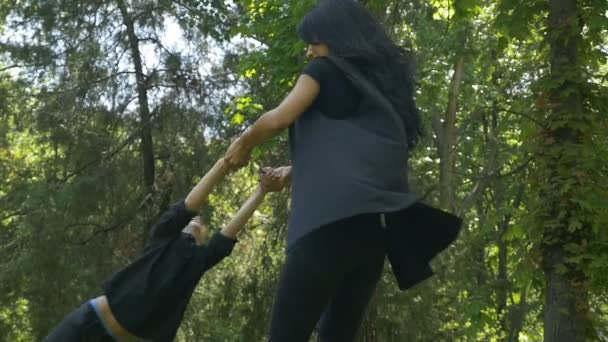 Медленное движение счастливой матери, крутящей ребенка в парке, играя и веселясь — стоковое видео