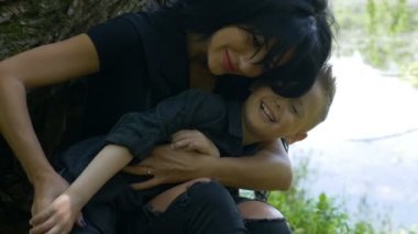 Sarılma ve çocuğunu bir lake Park yakınlarında oturan okşama çekici kadın