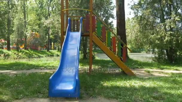 Jovem menino feliz jogando no parque público em um slide — Vídeo de Stock