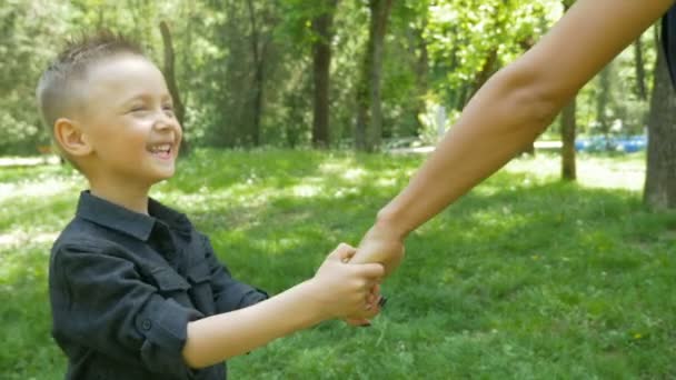 Мальчик спрашивает свою мать, может ли он играть с ним, хватая и дергая ее за руку — стоковое видео