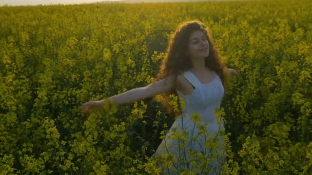 Junge Frau fühlt sich glücklich und dreht sich im Rapsfeld und genießt die Natur — Stockvideo