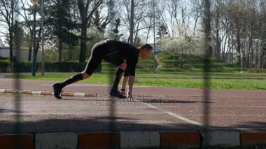 Başlangıç çizgisine blok başlangıç konumundan gecenin ağır çekimde yarış pisti üzerinde çalışan, atlet