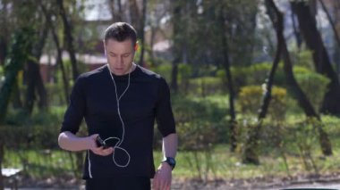 Koşan adam ve müzik ve hızlı bir dinlenme sosyal ortam iletileri smartphone bak.