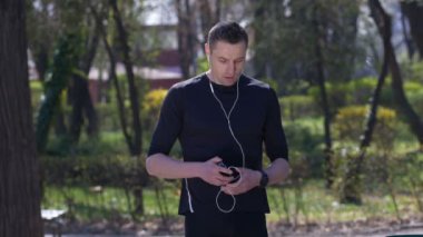 Erkek atletik jogger smartwatch counter ayarlama ve onun smartphone kontrol için çalışmayı durdurur