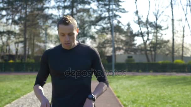 Närbild av trött ung idrottare i träningsoverall stoppa att vila efter jogga i parken sedan börjat köra — Stockvideo