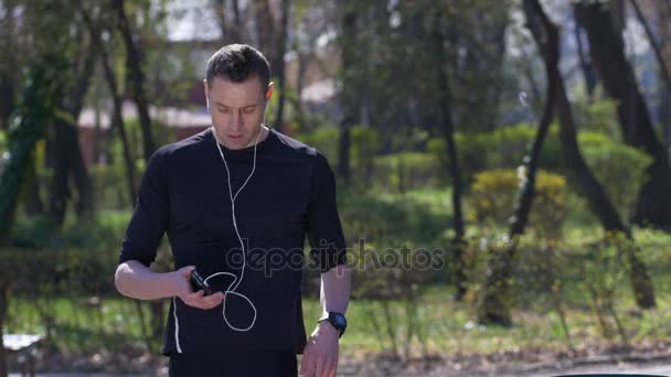 走っている人が音楽を聴くと迅速な休憩を見てソーシャル メディア メッセージのスマート フォンで — ストック動画